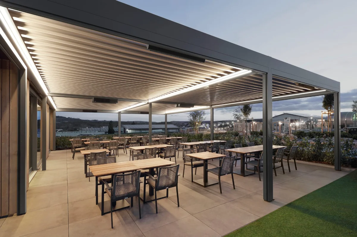 Terrassenüberdachung mit dem Lamaxa Lamellendach Moderne überdachte Terrasse in der Gastronomie bei Sonnenuntergang